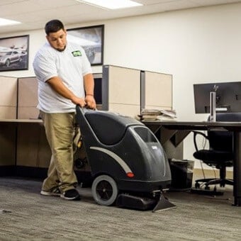 Professional cleaner using carpet cleaning machine in office