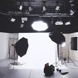 Film production studio heavily lighted with white backdrop