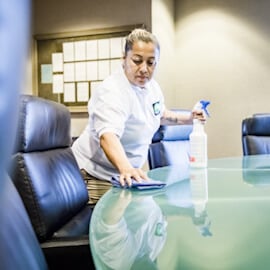 Professional cleaner wiping glass conference table